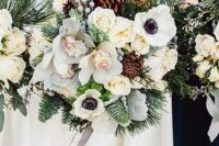 a pretty winter wedding bouquet of white anemones and orchids, evergreens, pinecones, berries and grey ribbon is a chic idea