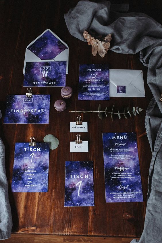 a purple galaxy-themed wedding invitation suite with white letters and numbers, stars printed on them is a gorgeous idea