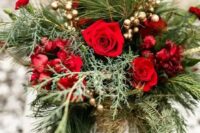 a romantic Christmas wedding bouquet of greenery and fir, gilded berries, red and burgundy blooms