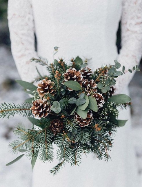 a simple and cozy winter wedding bouquet of evergreens, eucalyptus and snowy pinecones
