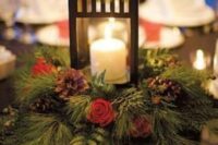 a simple and cute winter wedding centerpiece of evergreens, pinecones, berries and a large candle lantern is very cozy