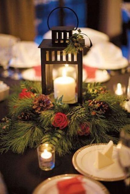 a simple and cute winter wedding centerpiece of evergreens, pinecones, berries and a large candle lantern is very cozy
