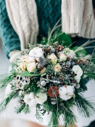 a snowy wedding bouquet of evergreens, berries, white and rust blooms, berries, twigs, lotus slices is amazing