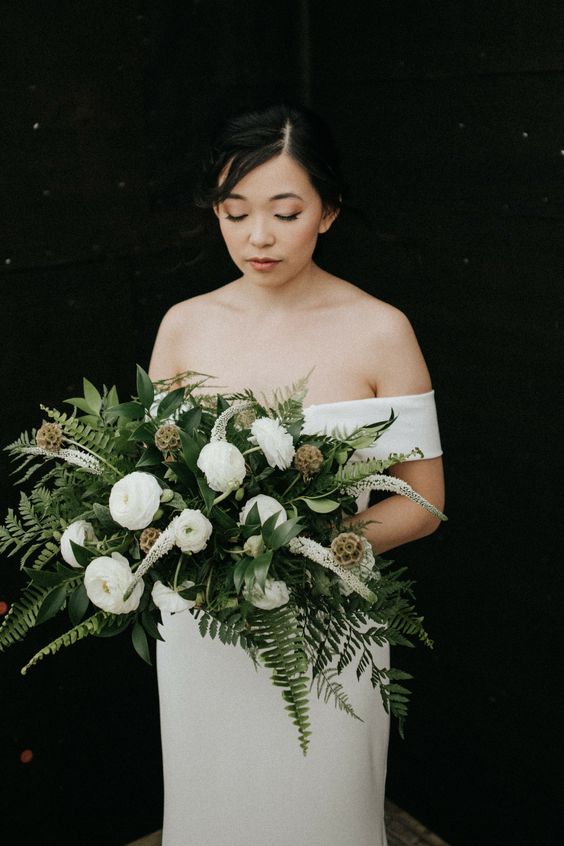 a sophisticated wedding bouquet of fern, white ranunculus, astilbe, seed pods is a refined idea for any bride