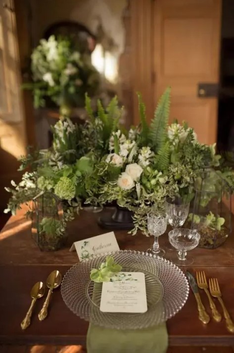 a super cool textural and dimensional greenery wedding centerpiece with white blooms and candle lanterns is amazing for an enchanted forest wedding