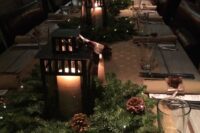 a super cozy winter wedding centerpiece of a lush evergreen wreath, lights, pinecones and a large candle lantern is wow