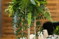 a tall wedding centerpiece of eucalyptus, fern and other greenery is a stylish modern solution for a wedding