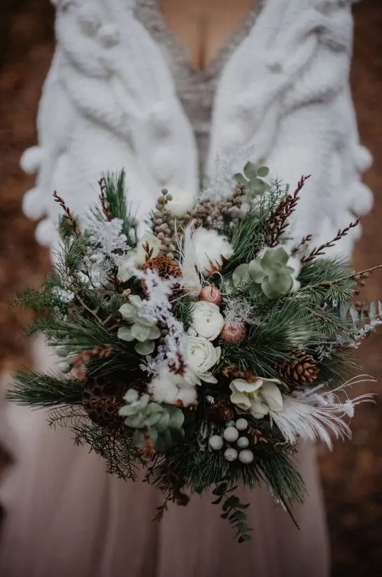 a textural winter wedding bouquet of evergreens, greenery, twigs, berries, pinecones, cotton, feathers and lotus is amazing