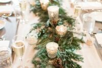 a winter wedding table runner of evergreens, pinecones and shiny candleholders with candles is a lovely idea for any type of winter wedding