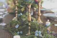 an evergreen table runner with blue flowers and blueberries, dotted with candles, for a natural feel