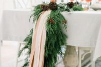 an exquisite winter table runner of evergreens, pinecones and blush ribbons will fit even the most refined winter wedding and will give ti a cozy feel