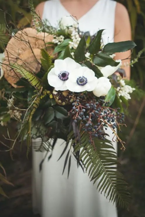 an eye-catchy woodland wedding bouquet with white blooms, privet berries, foliage and twigs is a very catchy dimensional piece