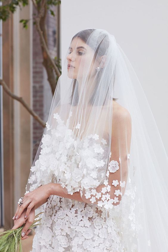 a cathedral veil with white flower applique and a matching wedding dress for a refined haute couture look at the wedding