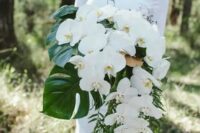 02 a lush cascading wedding bouquet with large monstera leaves and white orchids for an elegant feel