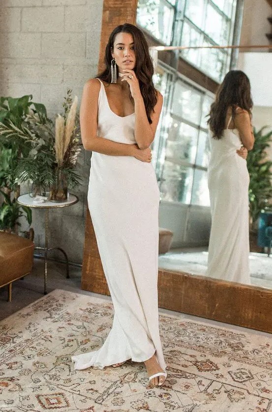 a modern relaxed plain slip wedding dress with a deep V-neckline plus statement earrings for an edgy look