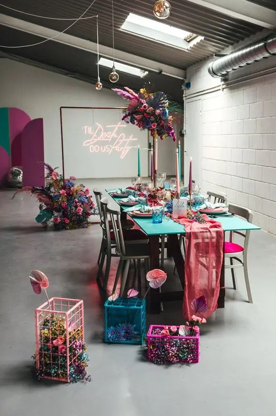 a colorful wedding reception space decorated in hot pink, fuchsia, turquoise, blue, violet, with blooms, cages and candles