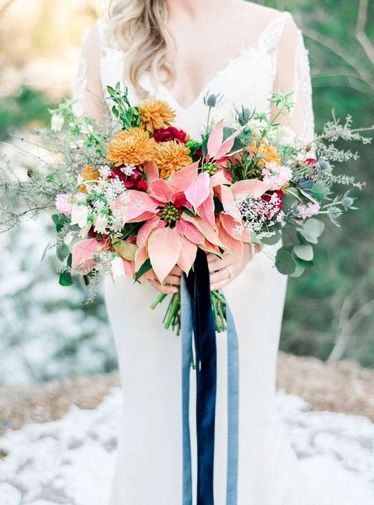 a lovely wedding bouquet of pink poinsettias, mustard, pink and white blooms, greenery and thistles is a beautiful idea