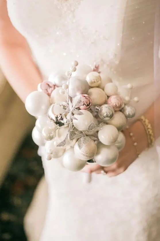 a delicate winter wedding bouquet made of white, silver and pink ornaments and silver faux berries and leaves is wow