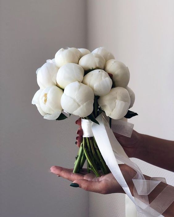 a white peony wedding bouquet with white ribbons is a classic and beautiful idea for a bride, for any season and style