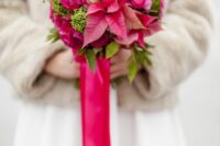 06 a bold wedding bouquet with hot pink ranunculus and poinsettias, greenery and green berries plus long pink ribbons