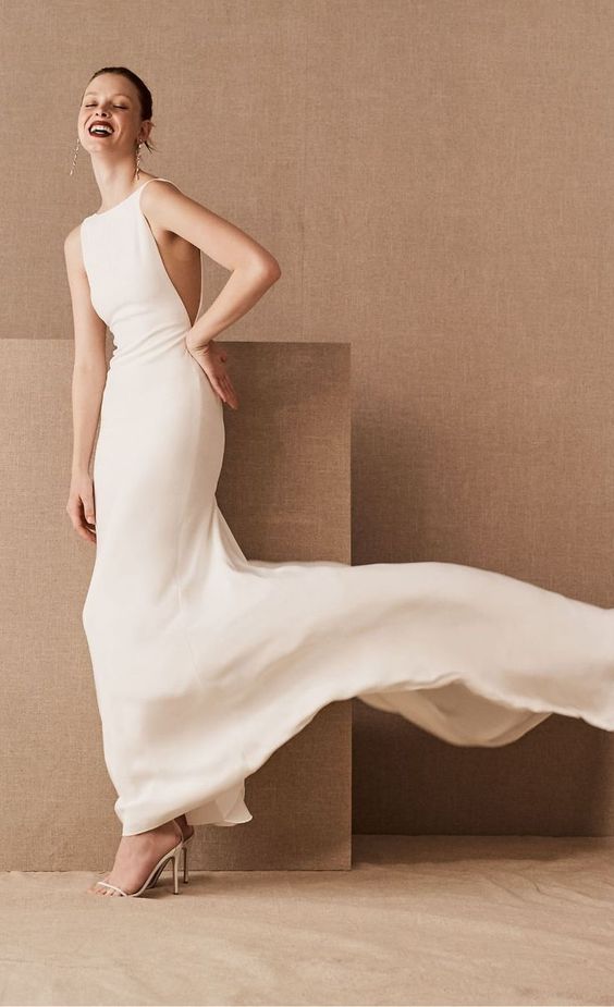 a minimalist bateau neckline semi-fitting wedding dress with no sleeves, side cutouts and a train is wow