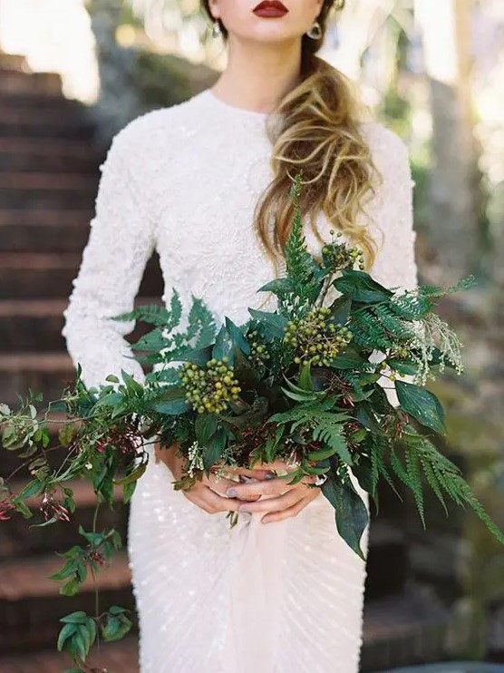 A lush textural greenery wedding bouquet of various kinds of foliage, berries will fit many weddings including a modern NYE one