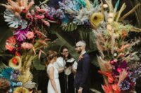 09 a bright and colorful wedding arch with bold blooms, pampas grass, tropical leaves and spray painted fronds is wow