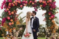 10 a colorful tropical wedding arch with hot pink, light pink, rust, yellow and orange blooms and monstera leaves is a gorgeous decor idea