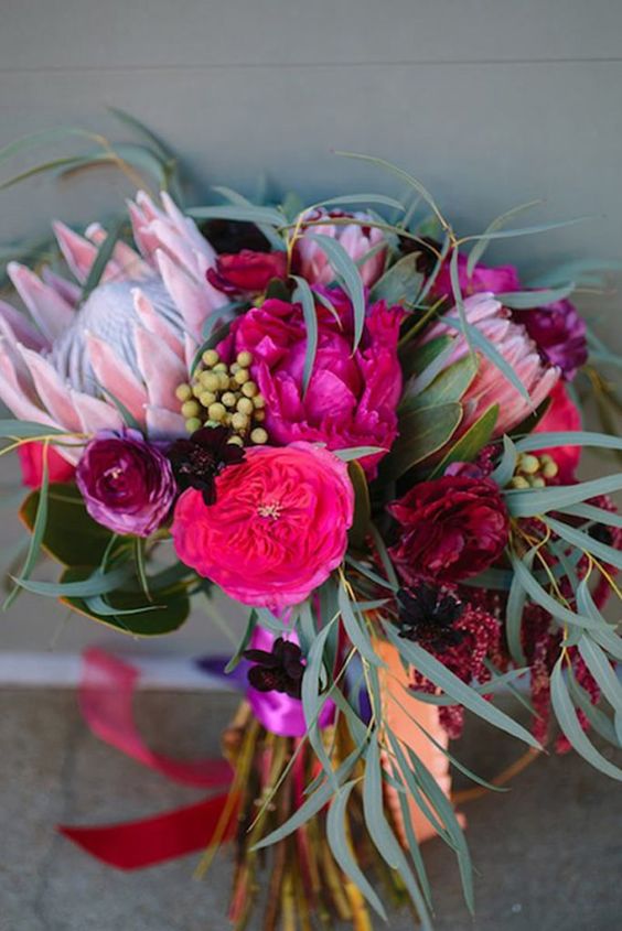 a bright and chic wedding bouquet with hot pink, fuchsia blooms, king proteas, greenery and grasses is great for the fall