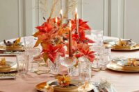 14 a bold and chic wedding tablescape with a pink tablecloth, gold chargers, a large centerpiece of poinsettias in glasses and rust-colored candles