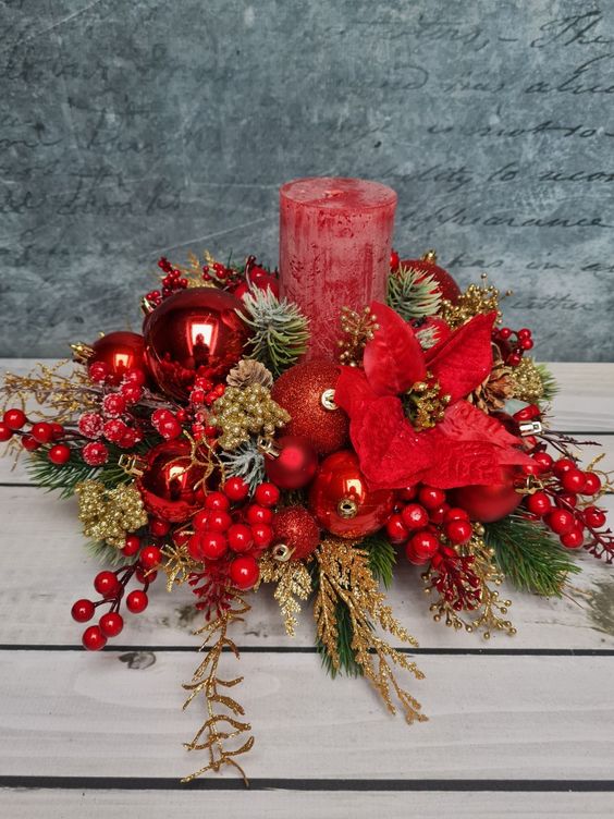 a bold Christmas or Christmas wedding centerpiece of red ornaments, berries, gilded pinecones and branches and red poinsettias