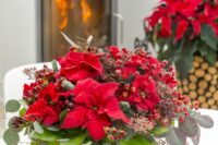 16 a bold Christmas wedding centerpiece of red poinsettias, berries, evergreens, leaves and foliage is a chic idea