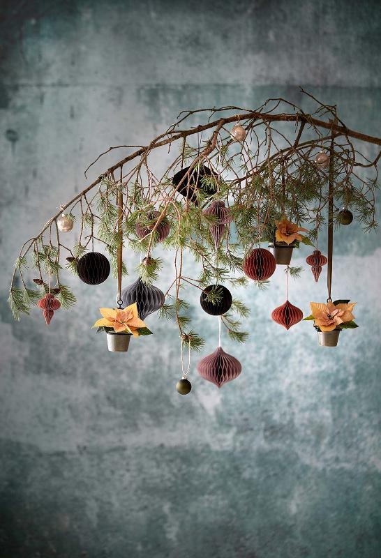 a catchy wedding decoration of a branch with paper ornaments and potted poinsettias is a creative idea for winter holidays
