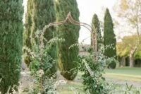 17 an enchanting garden wedding arch of a whimsy shape, with greenery and lots of blush blooms climbing up the arch