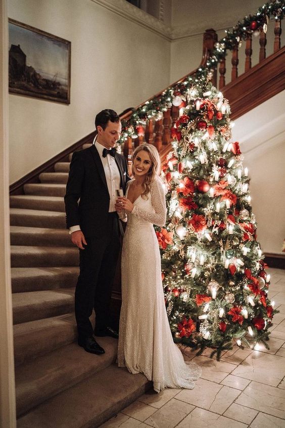 a Christmas tree as a wedding decoration, with lights, red poinsettias and other decor looks adorable and classic