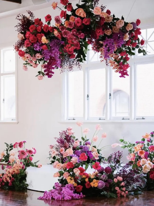 a bright wedding ceremony space with red, peachy, hot pink and fuchsia blooms and greenery is a very bold and catchy space