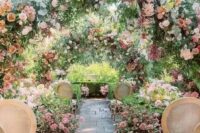 19 a pastel flower garden wedding ceremony space with greenery and pink bloom arches and floral arrangements on the ground