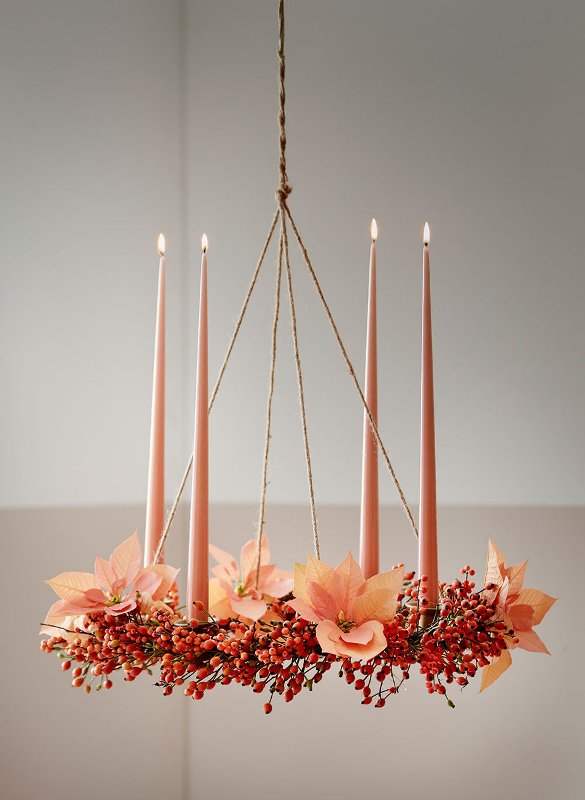 a Christmas wedding decoration, a chandelier covered with berries and poinsettias plus pink tall and thin candles