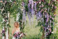 23 a very natural wedding arch with much greenery, purple and light pink blooms and some neutral fabric is wow