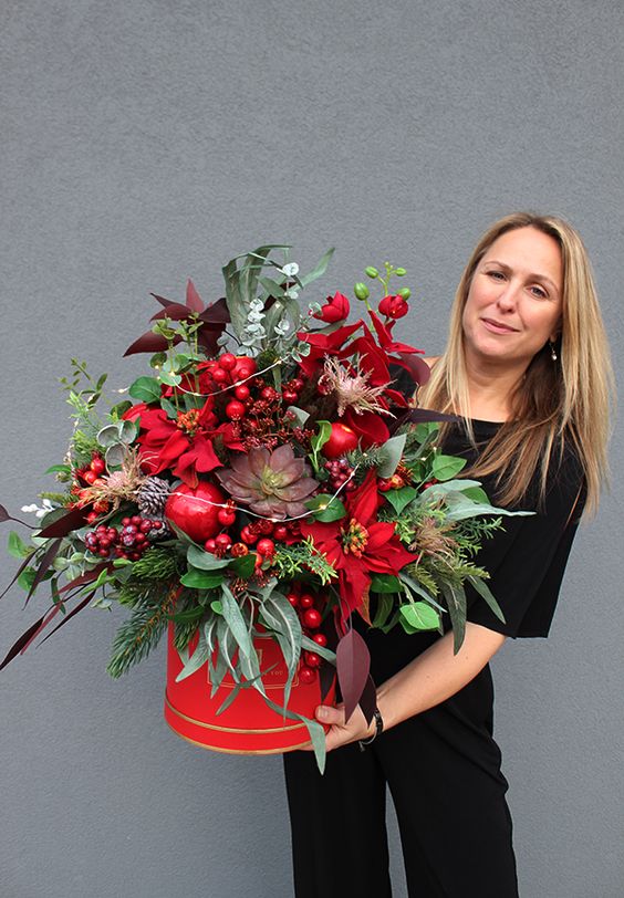 a fantastic wedding centerpiece of a red bucket, greenery and evergreens, red berries, pomegranates, poinsettias and LEDs