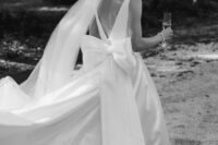 24 a refined wedding ballgown with a cutout back, a large bow, a long train plus a veil are a fantastic combo for a modern wedding