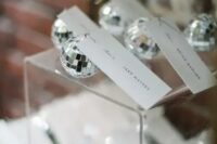 24 mini disco balls as wedding favors and as place card holders at the same time for a party-themed or a NYE wedding