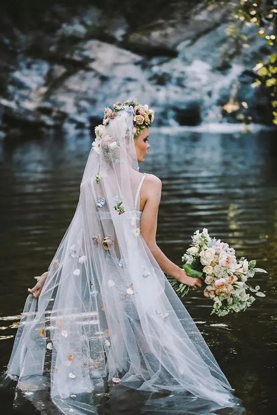 a long veil with a faux flower halo on top and pastel-colored faux blooms all over the veil for a catchy and very romantic bridal look