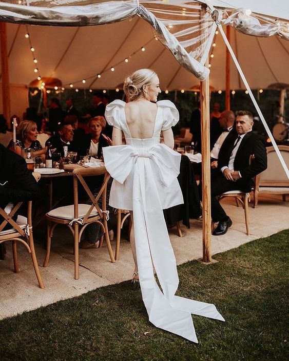 a cool modern mini wedding dress with a cutout back, puff sleeves, a large bow on the back is a fantastic idea
