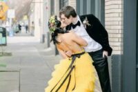 27 a bold sunny yellow A-line wedding dress with spaghetti straps, an open back and a tiered ruffle skirt with a train plus a black ribbon belt