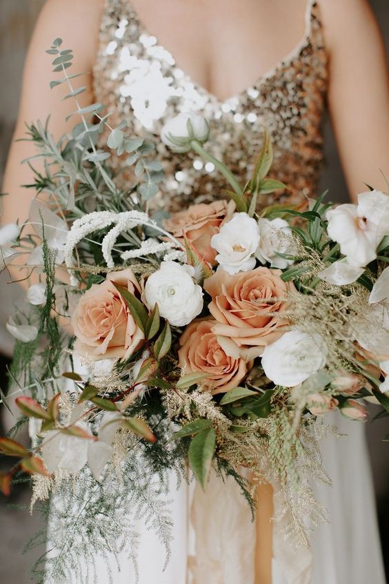 a soft-colored NYE wedding bouquet with peachy and white blooms and greenery plus some grasses is a lovely idea