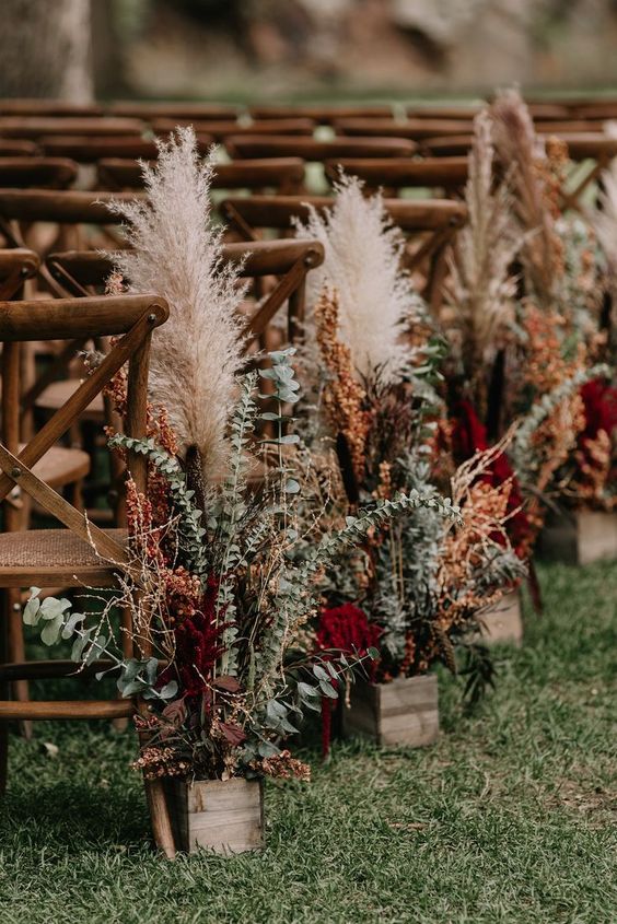a wedding aisle lined up with eucalyptus, burgundy and rust blooms and pampas grass is ideal fro a Western wedding