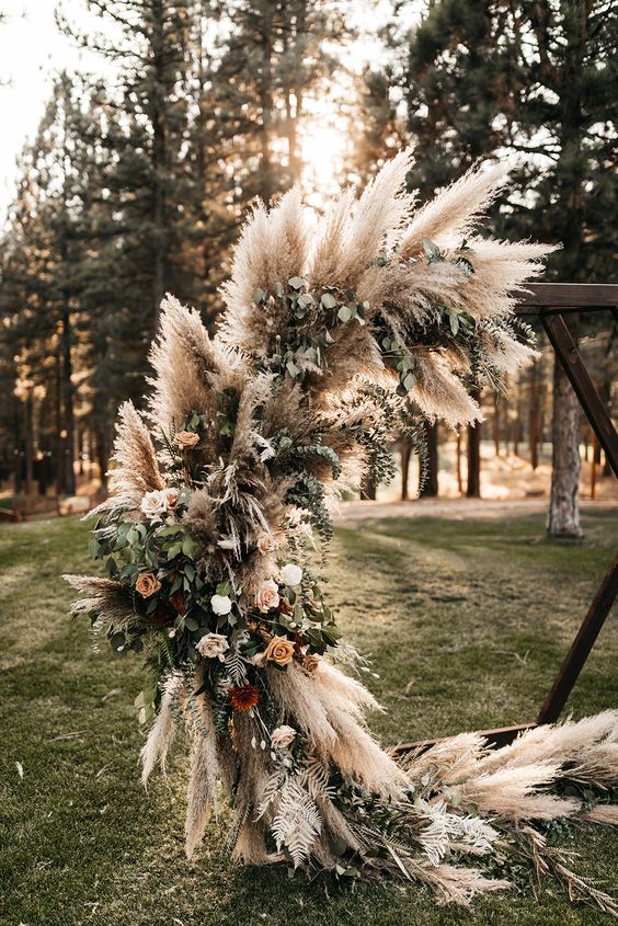a round wedding arch decorated with pampas grass, roses of various shades and greenery is great for a Western boho wedding