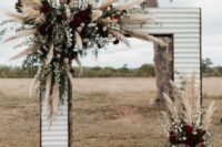 35 a Western wedding arch done with blusha nd burgundy blooms, greenery and pampas grass plus a cowhide rug