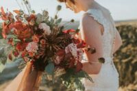 35 a bold and lush fall wedding bouquet of pink, rust, deep red and deep purple blooms, greenery, seed pods and long ribbons is amazing